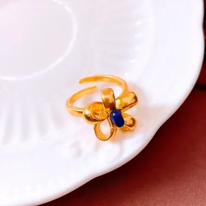 Vintage gold bow open ring with a blue gemstone on a decorative porcelain plate