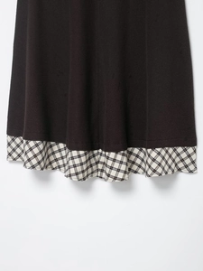 Détail de l'ourlet d'une robe marron avec empiècement à carreaux noirs et blancs