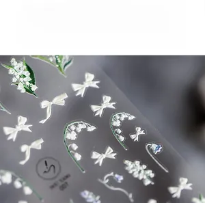 Vue macro d'autocollants pour ongles muguet et nœuds blancs avec texture en relief