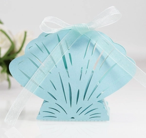 Close-up of light blue laser-cut shell gift box with translucent white ribbon and floral decor