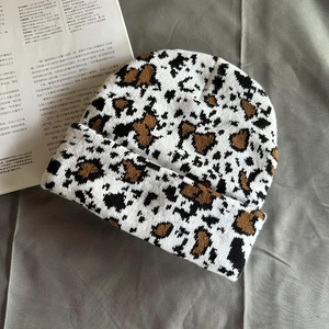 Macro shot of thick leopard print knit beanie with soft vintage texture on grey fabric
