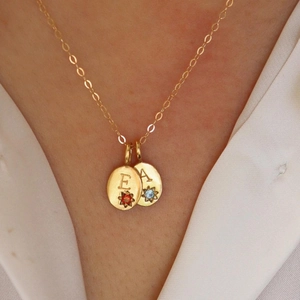 Gouden titanium stalen ketting met A en E letter hangers gedragen door een model