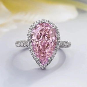 Detailed close-up of a pear-cut pink zircon ring with halo diamond setting and pavé band