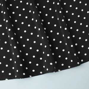 Detail of black polka dot dress fabric showing high-quality stitching and seam work