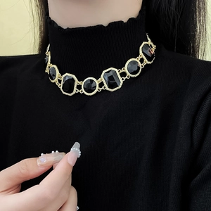 Detailed view of a vintage gold necklace with large black octagonal crystals on a model