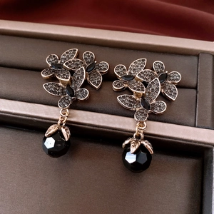 Macro view of vintage floral earrings featuring dark rhinestones and black faceted beads