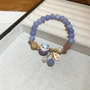 Detailed view of lavender beaded bracelet with Maneki Neko charm and gold blessing tag