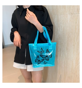 Fashionable blue transparent PVC tote bag with black butterfly prints worn by a model