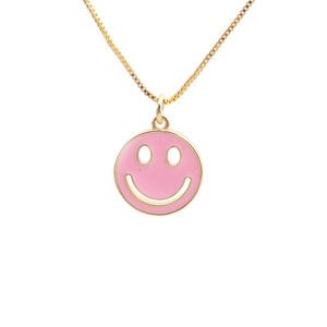 Minimalist gold necklace featuring a pink enamel happy face charm on a white background