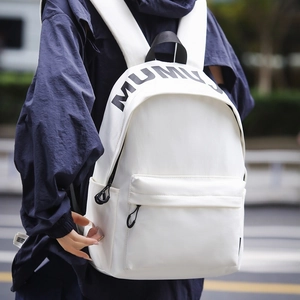 Minimalist white backpack with black MUMU logo shown on a model in an urban setting