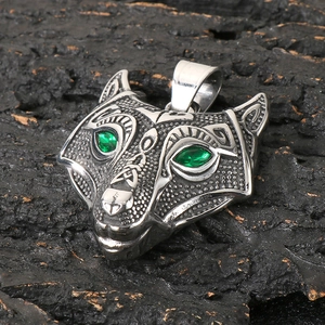 Close-up of viking wolf head pendant with green gem eyes on dark rock texture