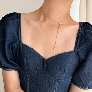 Close-up of a gold-plated titanium Y-shaped necklace with star and moon tassels on a model