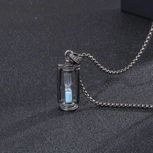 Macro shot of hourglass pendant featuring blue sand and vintage stainless steel finish