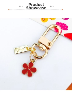 Close-up of golden metal keychain featuring red flower charm and Handmade engraved tag
