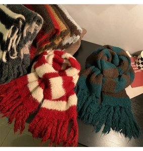 Detailed texture of knitted plaid scarves with soft fringes in red and green colors