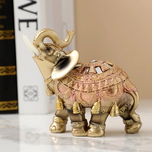 Close-up of golden and pink resin elephant ornament with ornate hollow-carved patterns