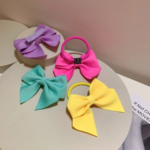 Vibrant oversized fabric bow hair clips and ties in pastel neon colors displayed on podiums
