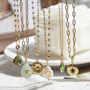 Macro detail of French vintage gold necklaces with natural stone and baroque pearl charms