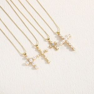 Elegant gold cross necklaces with pearls and zircons on white textured background