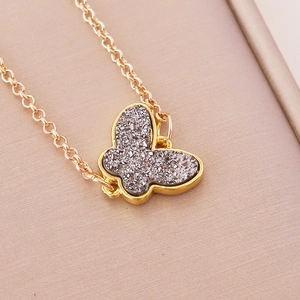 Detailed macro view of a gold-framed butterfly pendant necklace with sparkling grey inlay