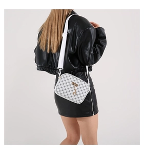 White shoulder bag with deer pendant shown on model in studio setting