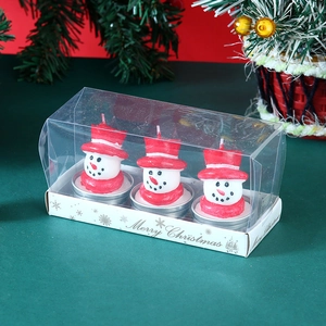 Three snowman Christmas candles in festive red and white gift packaging on table
