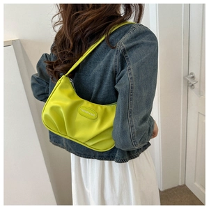 Détail du sac à bandoulière croissant vert clair avec plaque de lettre et design plissé chic