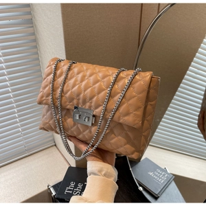 Close-up of beige quilted crossbody bag featuring silver turn-lock and chain strap