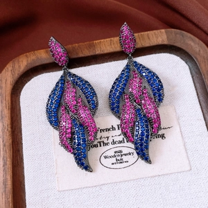 Macro shot of vintage style teardrop earrings with blue and pink zircons in a jewelry box