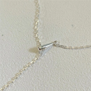 Macro shot of minimalist silver water drop pendant and fine chain texture detail