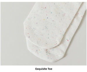 Close-up of beige knit socks showing colorful speckles and detailed stitching at the toe