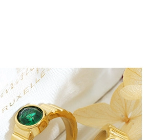 Close-up of vintage gold chunky ring featuring a round green gemstone and textured engraving