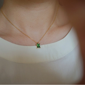 Minimalist gold titanium necklace with emerald-cut green gemstone pendant on model