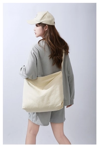 Dettaglio della grande borsa tote in tela di cotone crema indossata da una modella