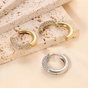 Macro detail of 14K gold and silver chunky C-shaped hoop earrings with zircon pavé stones