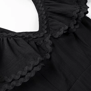 Dettaglio dello scollo a V con bordi a balze e finiture rickrack sull'abito nero
