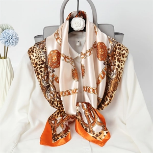 Close-up of silk scarf with leopard print and gold chain pattern on a white shirt