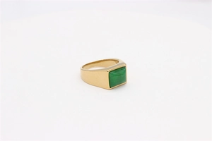 Macro view of a gold square signet ring with green gemstone on a white background