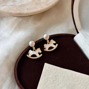 Gold plated rocking horse earrings with pearls and rhinestones on a velvet gift box