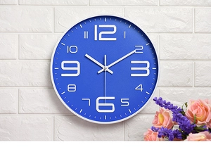 Detail of 10-inch navy blue wall clock with white 3D numbers on a white brick wall
