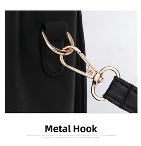 Detail of light gold lobster clasp hardware and neat stitching on black faux leather bag