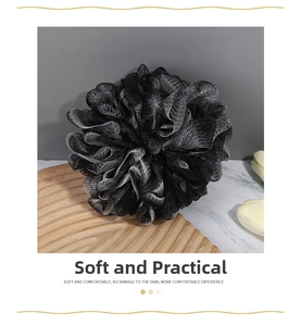 Close-up of black and white charcoal bath sponge on a wooden base with fine mesh texture