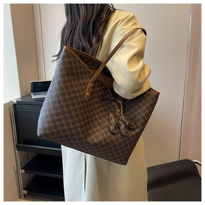Detail of the high-capacity monogram tote bag with brown leather straps and doll charm