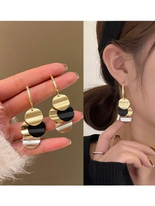 Detail showing vintage multi-color metal disk tassel earrings on a model and hand-held