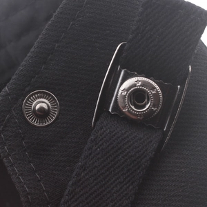 Detail of black twill fabric with star-embossed metal snap button on a beret hat