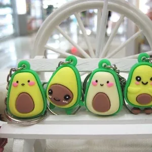 Cartoon avocado keychain set with four cute expressions on a white wooden stand