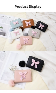 Close-up of bow knot detail and fluffy pompom charm on a stylish women's short wallet