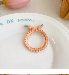 Detail of peach pink elastic hair tie with wavy edges and sky blue accent on ceramic tray