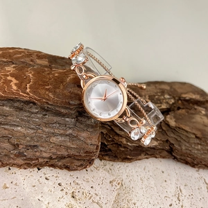 Rose gold bracelet watch with crystal stones displayed on natural wood and stone base