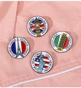 Detail of four enamel pins with world landmarks pinned on pink denim fabric